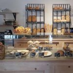 photo de l'intérieur d'une boulangerie à Pau (64), vue sur la vitrine sèche et les produits à vendre ainsi que sur les étagères de pains en arrière-plan