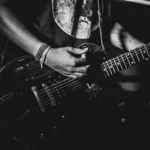 photo noir et blanc cadrée sur l'instrument et l'avant-bras d'un guitariste