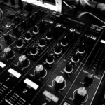 photo noir et blanc cadrée sur les pistes d'une table de mixage audio