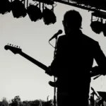 photo noir et blanc d'un guitariste sur scène vu de dos