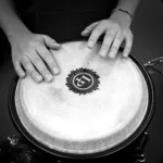 photo noir et blanc recadrée sur un djembe et les mains du musicien