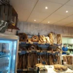 photo de l'intérieur d'une boulangerie, vue sur les étagères de pains et une partie du comptoir