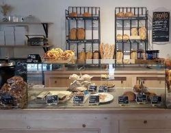 photo, intérieur d'une boulangerie, vue sur la vitrine sèche et étagères de pains en arrière-plan